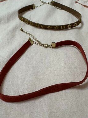 Set of 2 adjustable suede look chokers with gold details.